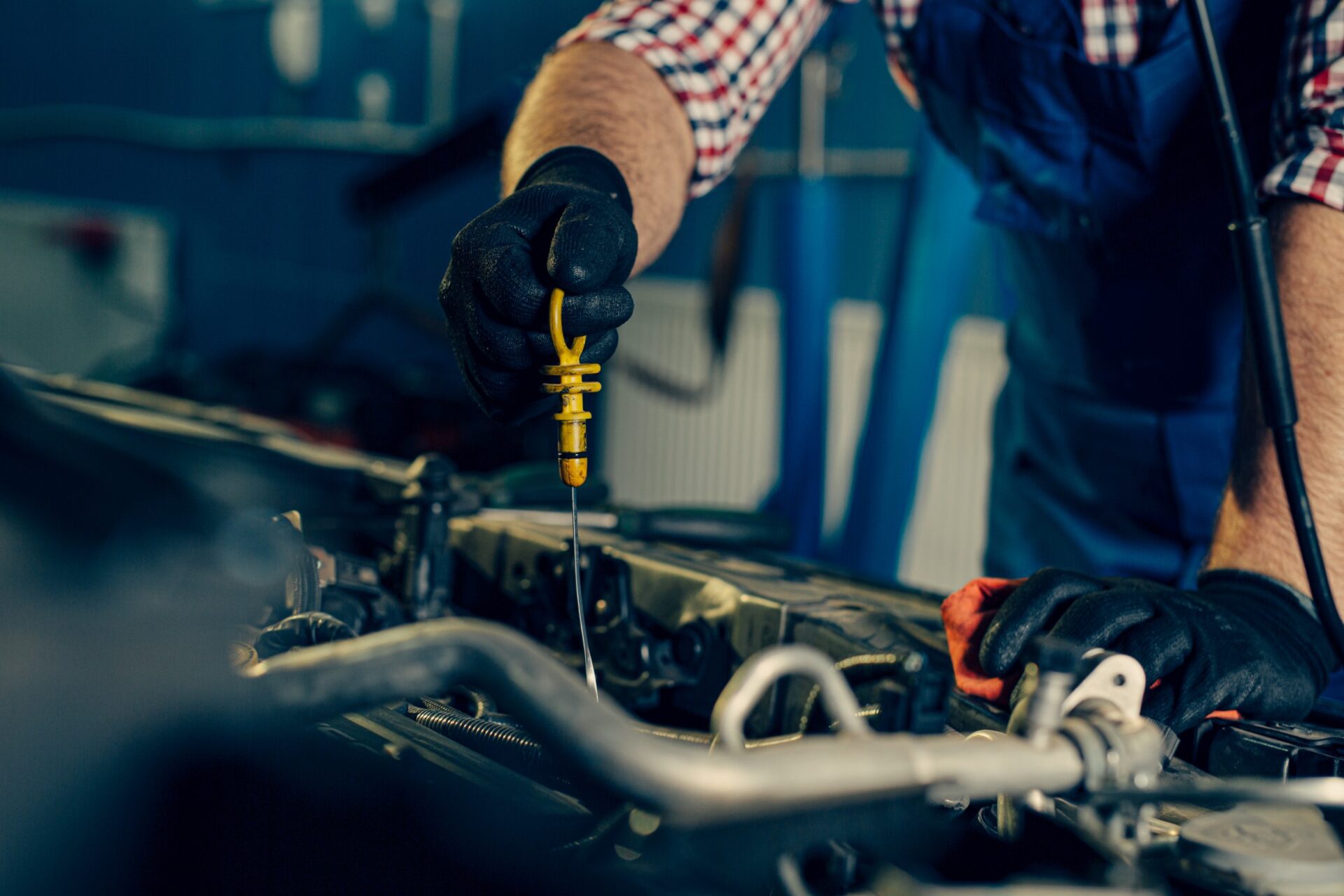 Car mechanic checking oil level in a mechanical workshop Car mechanic checking oil level in a mechanical workshop