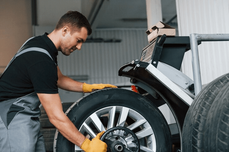 Taking the wheel Man in uniform is working in the auto service Taking the wheel Man in uniform is working in the auto service